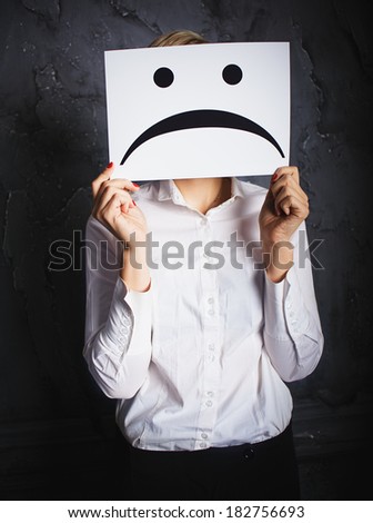 woman holding frames with sad faces. concept photo over dark background