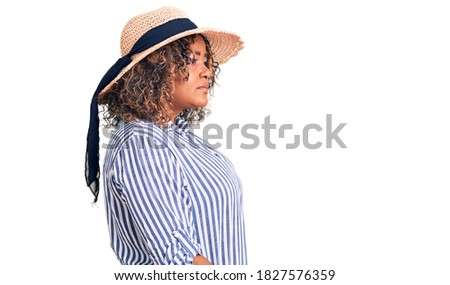 Young african american plus size woman wearing summer hat looking to side, relax profile pose with natural face with confident smile. 