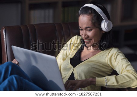 Happy Asian woman listening to music with the laptop.