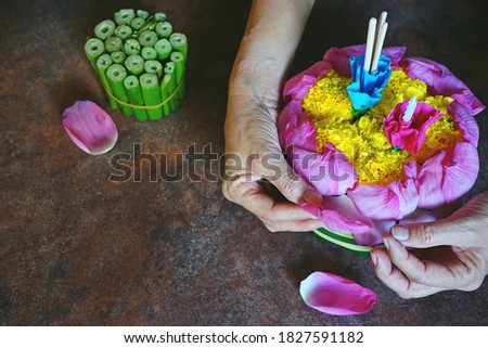 People making and decorating Krathong or lotus shaped vessel made of lotus petals and Water Hyacinth contained a candle, three joss sticks and some flowers for Loy Krathong Festival in Thailand.