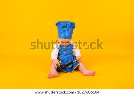 a focused little girl sits in a chef costume with a whisk on a yellow background with space for text