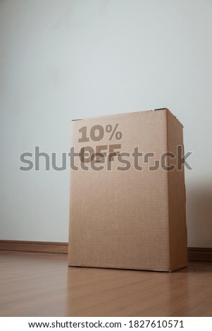 Cardboard box with 10% off order written on the box placed on the floor in an empty room with a neutral background. delivery concept. economy concept. business concept. shopping concept. copy space.