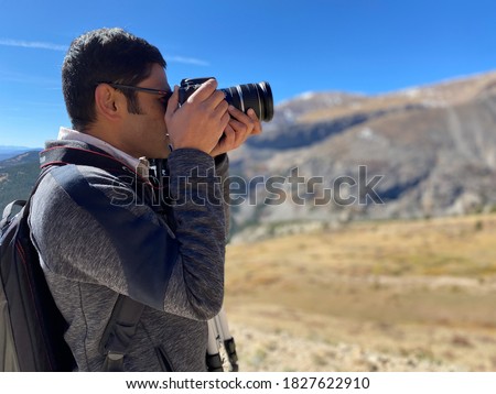 Cell phone portrait mode photo shoot of Indian man photographer holding a camera taking scenic pictures