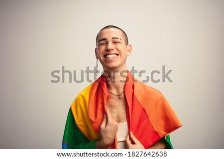 Cheerful transgender man with gay pride flag. Gender fluid male with lgbt flag against white background.