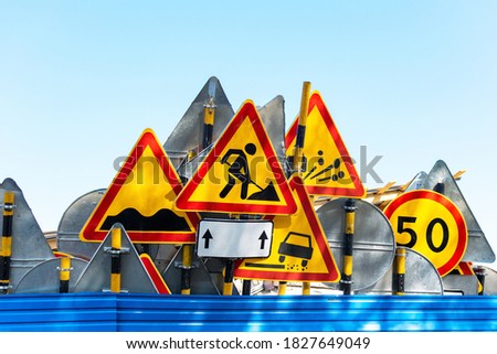Road repair concept. Group of yellow and red metall roadsigns for works in progress on a city street. Barriers and signs warning about work on the roadway, construction, traffic safety for vehicle.