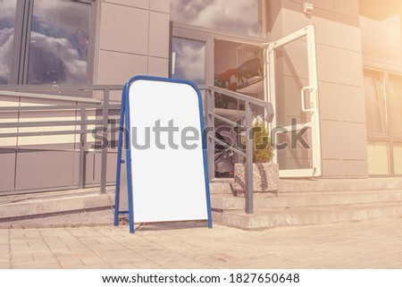 empty advertise stand in blue metal frame with mockup place on sidewalk near store open door side view