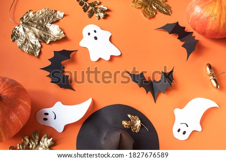 Halloween composition of black bats, white ghost on yellow background, pumpkins. Home handmade decor to celebrate Halloween.