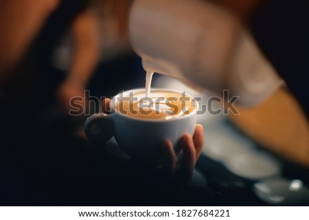 Professional barista pouring latte foame over coffee, espresso and creating a perfect cappuccino Royalty-Free Stock Photo #1827684221