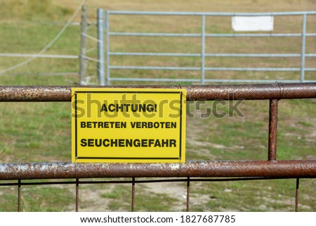 Yellow sign on a metal fence with the words  " Warning - Do not enter - Danger of epidemics "
