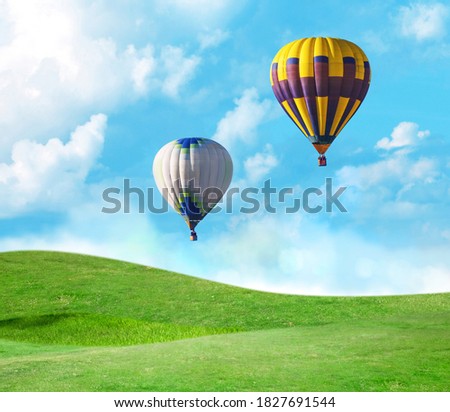 Fantastic dreams. Hot air balloons in blue sky with clouds over green meadow 