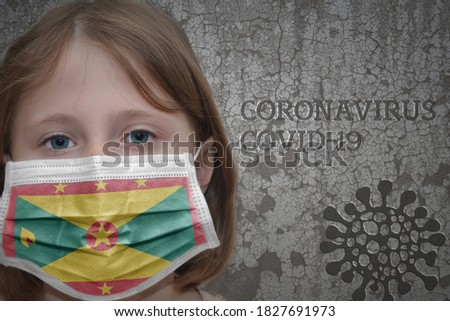 Little girl in medical mask with flag of grenada stands near the old vintage wall with text coronavirus, covid, and virus picture. Stop virus