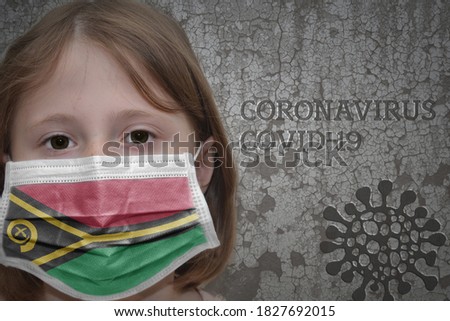 Little girl in medical mask with flag of Vanuatu stands near the old vintage wall with text coronavirus, covid, and virus picture. Stop virus