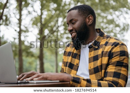 Portrait of happy African American student studying, learning language.  Business man using laptop computer, typing on keyboard, watching training courses. Smiling copywriter working freelance project
