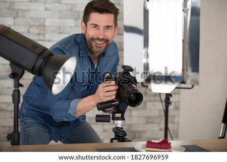 professional photographer in shirt holding hand on camera