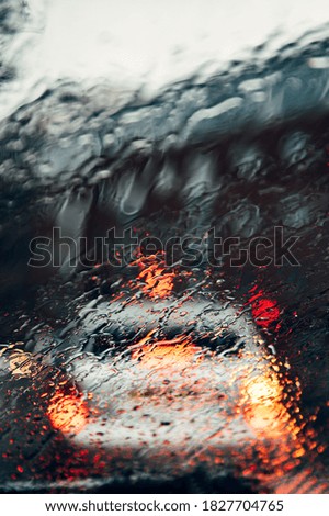 Blurred city street during dark rainy day, shoot throught car window with drops of rain
