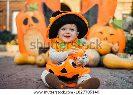 Child in pumpkin suit on background of autumn leaves