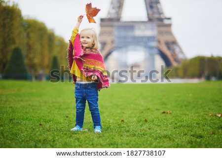 Adorable toddler girl near the Eiffel tower on a fall day in Paris, France. Child enjoying autumn outdoors