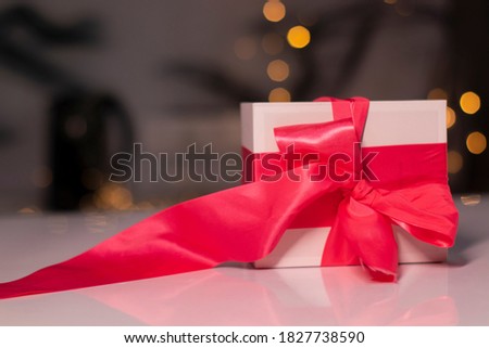 white gift box with pink ribbon bow on gold bokeh background. 
