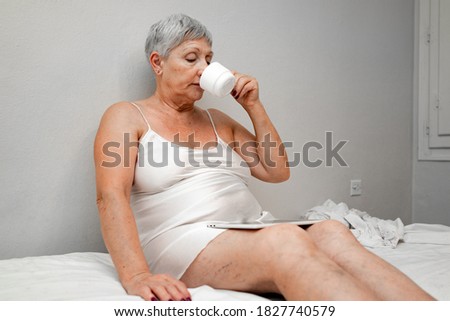 Caucasian older woman in bed with computer and coffee