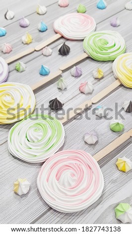 Colorful meringue lollipop on a grey background.
