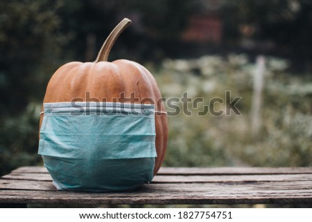 Halloween during quarantine. Pumpkin in a medical mask. Halloween and COVID-19. Halloween pumpkin on a wooden background, Holiday decoration.