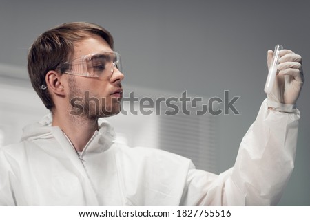 A young focused scientist in protective glasses looking closely at the precipitate in his test tube, a close up shot. Royalty-Free Stock Photo #1827755516