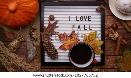 Flatlay letter board with sign love Fall Autumn composition . Cup of coffee on white letter board with fall autumn leaves on brown wooden background . Flat lay , top view .