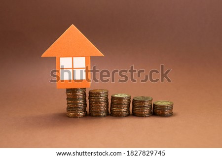 Stack of coins with house icon on brown background 