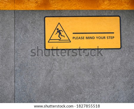 A yellow sign sticker indicates a sign showing a warning to beware of dangers from different areas on the wall