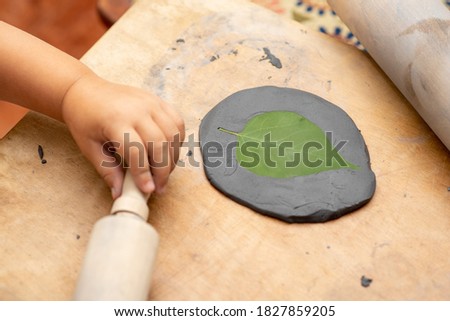 Child Sculpt Tree Leaf Print In A Black Clay.