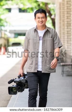 Portrait news cameraman broadcasting holding camera walking outdoor.