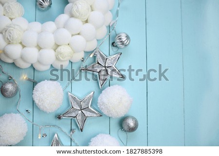 Christmas and New Year. silver decorative ornaments and white pompons on a blue wooden background.Winter festive cozy flat lay.