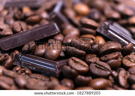 Close-up of dark roasted coffee beans and chocolate background. Aromatic coffee grains and sweet choco pieces macro photography, depth of field.