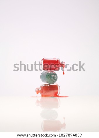 Three kind of nail polish dripping from bottle on white background