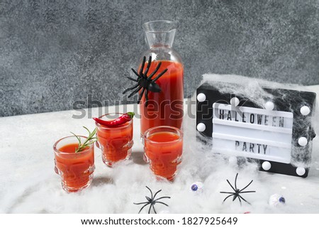 Bloody Mary cocktail or tomato juice in glasses shaped like skulls, Halloween decor cobwebs, spiders and eyes. Day of the dead food , selective focus