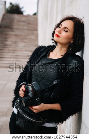 Beautiful young female photographer with camera outdoors 