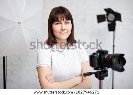 portrait of female photographer posing with camera and flashlights in photo studio