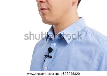 sound recording concept - close up of small lavalier microphone on male shirt isolated on white