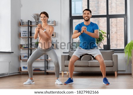 sport, fitness, lifestyle and people concept - smiling man and woman exercising and doing squats at home Royalty-Free Stock Photo #1827982166
