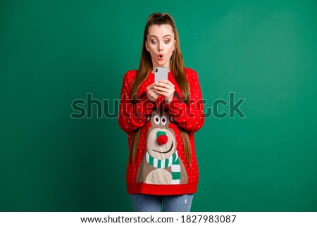 Photo of attractive shocked lady open mouth hold telephone open mouth read post comments wear red ugly ornament deer decor pullover sweater jeans isolated green color background