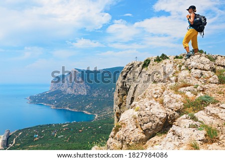 Young active woman stand on mount top looking at amazing sea landscape. Travel adventure, hiking activity, healthy lifestyle, exploring nature on summer vacation. Weekend day walking tour.