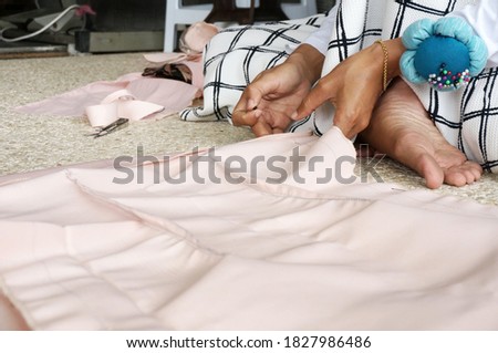 Closeup of a woman's hands pinning large upholstery pins into plain fabric, With Selective Focus                               