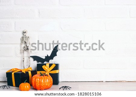 Halloween holiday background with gifts and decorations against a white brick wall. Copy space for text.