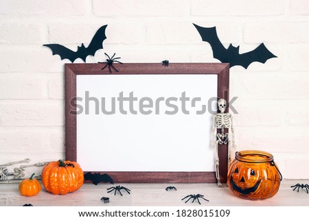 Empty wooden frame with Halloween decorations against white brick wall. Halloween holiday background. Copy space for design.