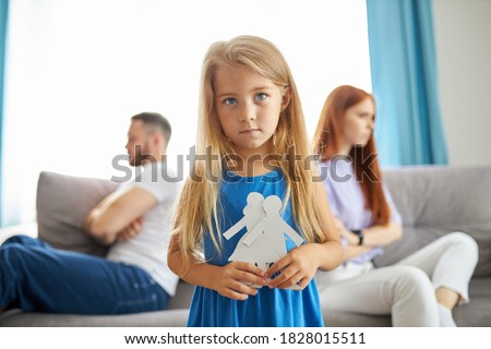 sweet little caucasian child girl holding family picture drawing feeling upset about parents divorce, innocent sensitive little kid suffer from trauma offended by fights conflicts shared custody Royalty-Free Stock Photo #1828015511