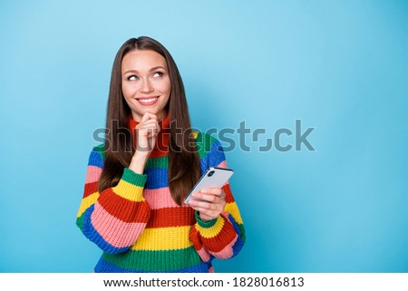 Photo of curious woman addicted blogger use smartphone think thoughts look copyspace touch fingers chin decide what texting typing wear rainbow style sweater isolated blue color background