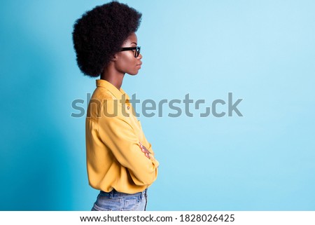 Side profile photo of dark skin big volume hairstyle lady folded hands self-assured calm look empty space listen boss wear specs jeans yellow shirt isolated blue color background