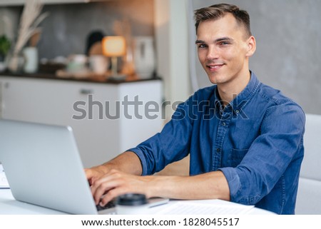 male freelancer works on a laptop in his kitchen.