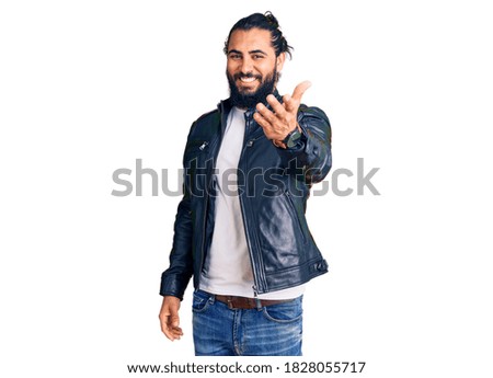 Young arab man wearing casual leather jacket smiling cheerful offering palm hand giving assistance and acceptance. 
