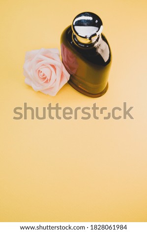 A bottle of nice perfume with a beautiful rose flower on a yellow background